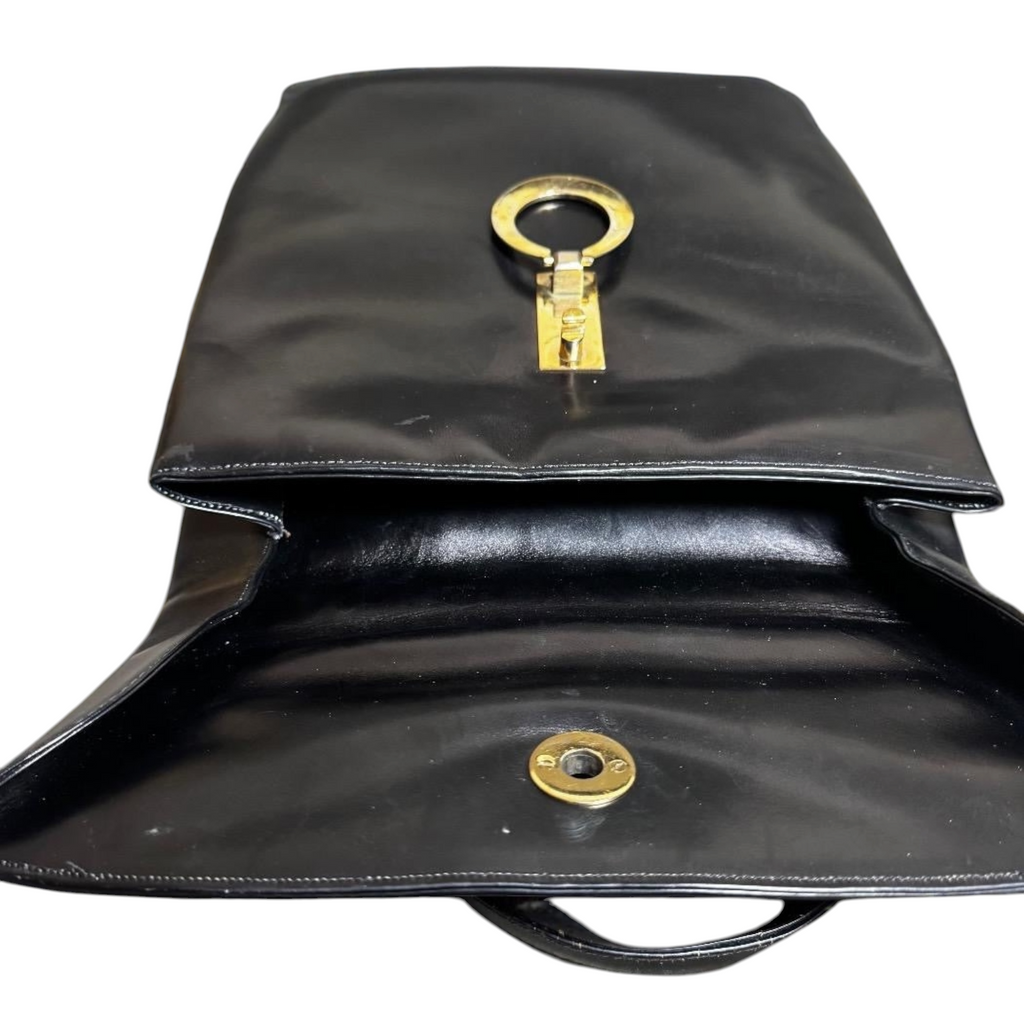 Borsa a mano vintage in pelle nera con chiusura a cerchio dorato.